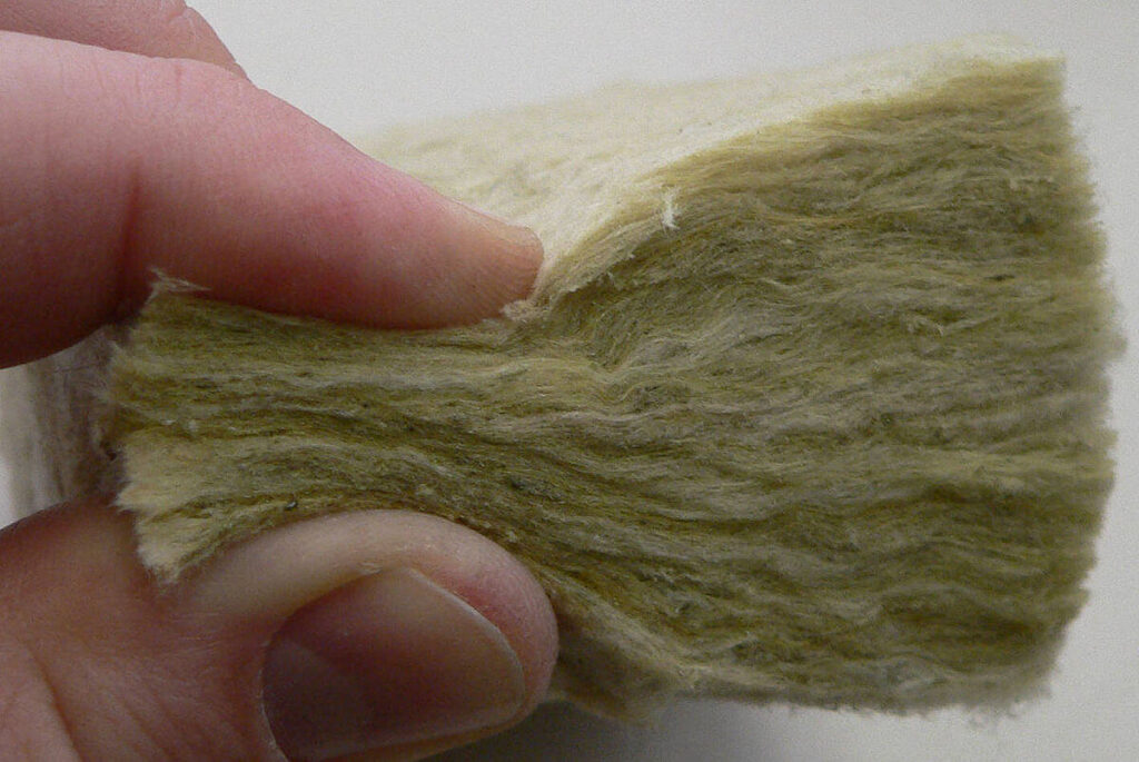 Main pinçant une épaisseur de laine de roche